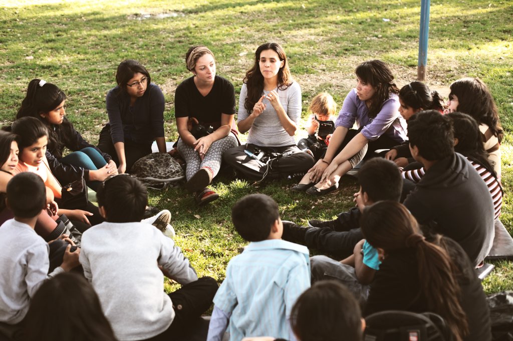 Brisa sits in a circle with a group of children in Bolivia.