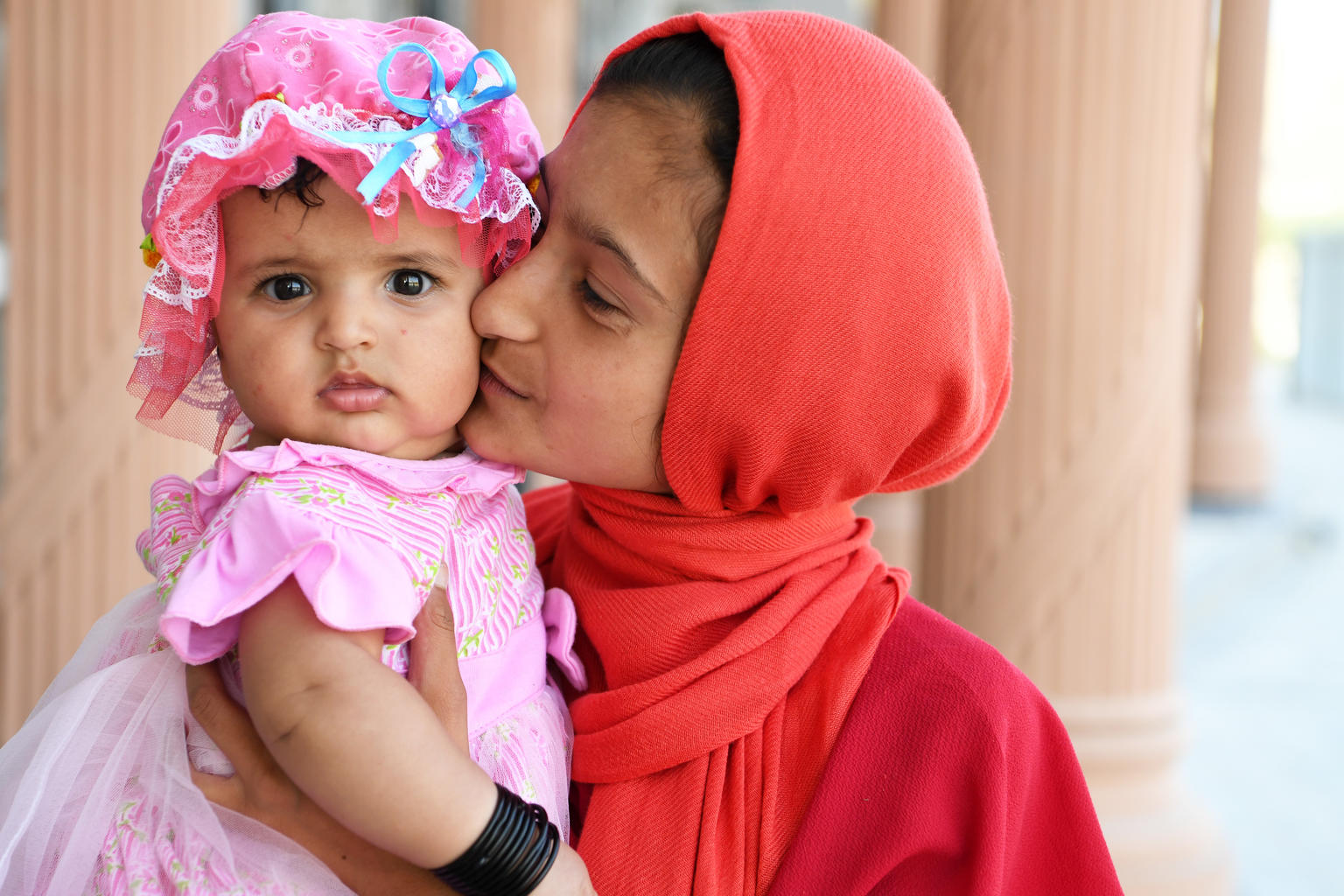 A girl kisses her baby sister in Afghanistan.