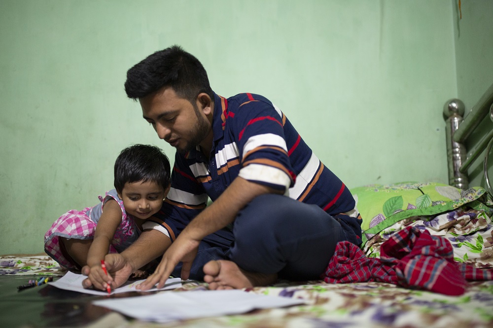  A child and his father draws at their home in Bangladesh. 