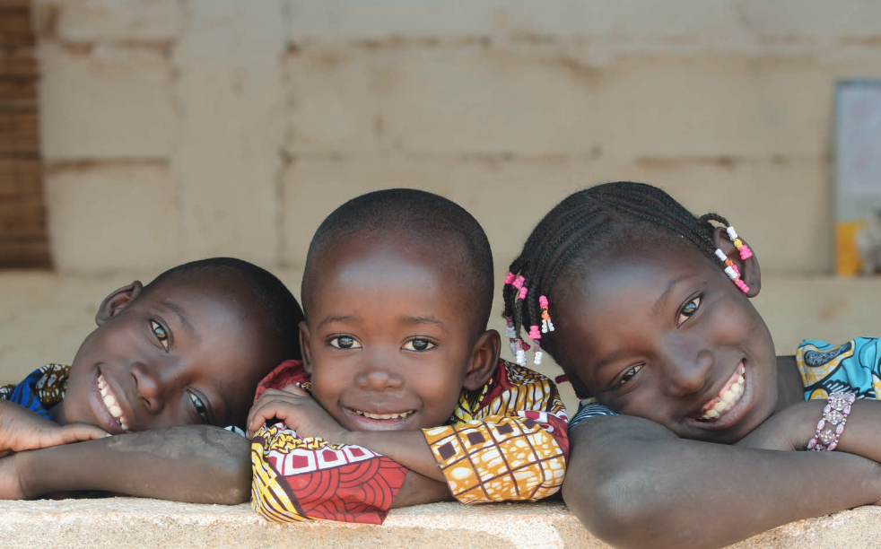 Three children smile in Africa.