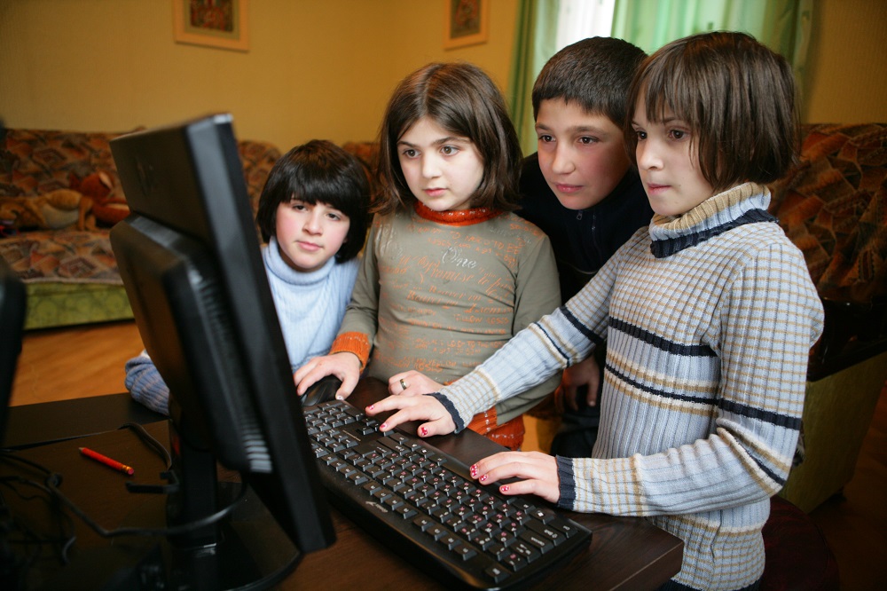 Children hover over a computer in Georgia. 