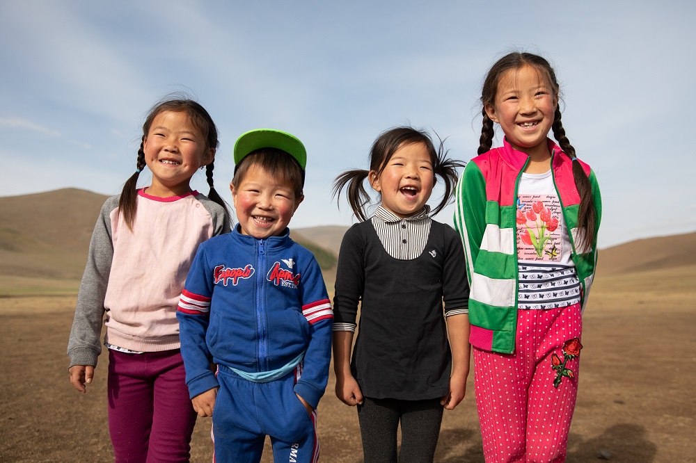 A group of children laugh outside in Mongolia. 