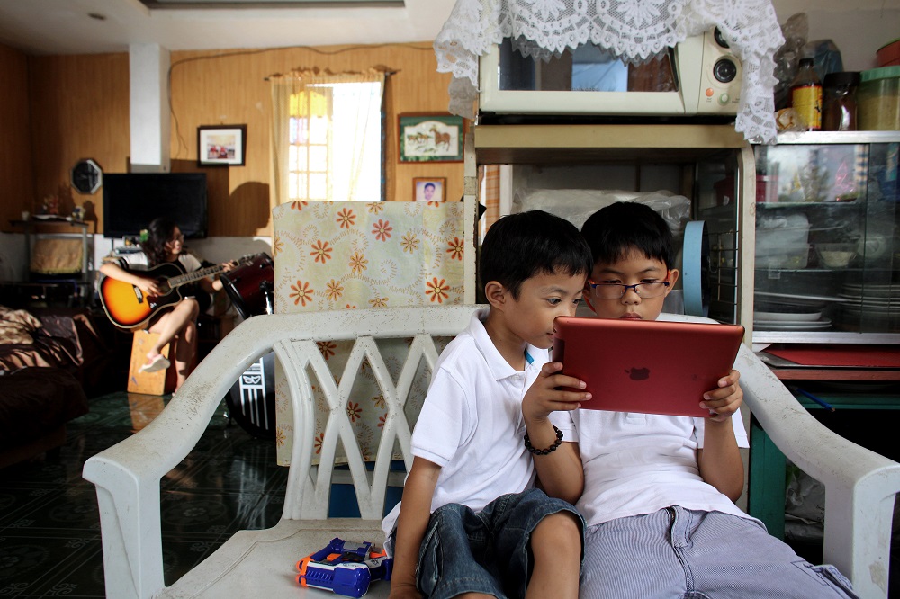 Two children in the Philippines gather around a tablet.