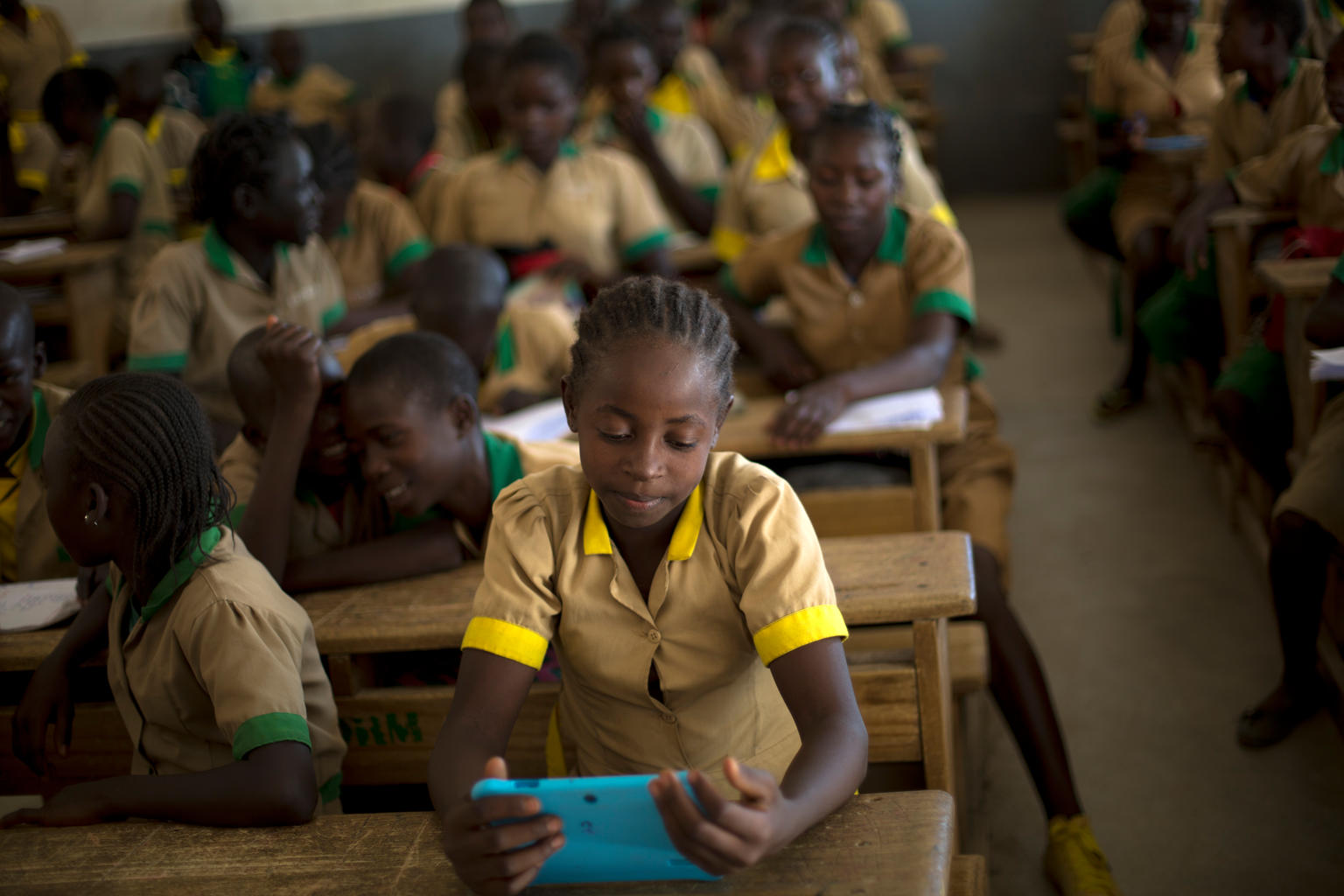 Children in West Africa look at a tablet at school.