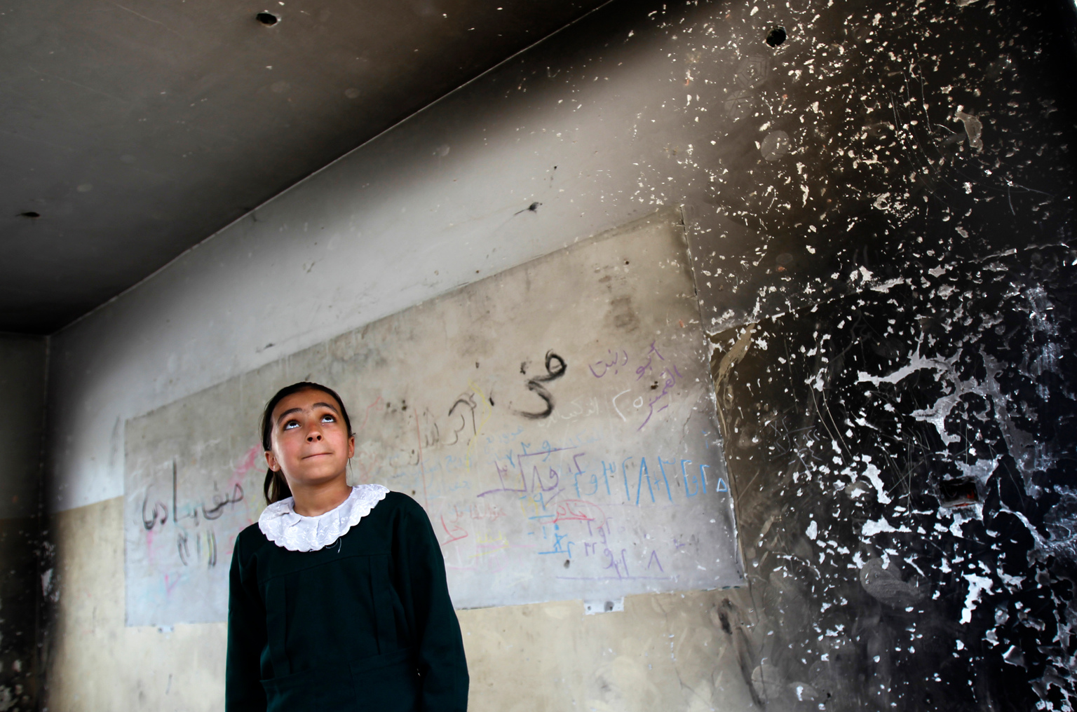 A student looks inside one of the classrooms destroyed by conflict in Gaza, the State of Palestine.