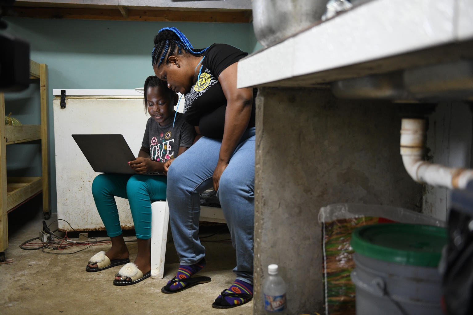 A child and her mother look at a computer in the Caribbean.