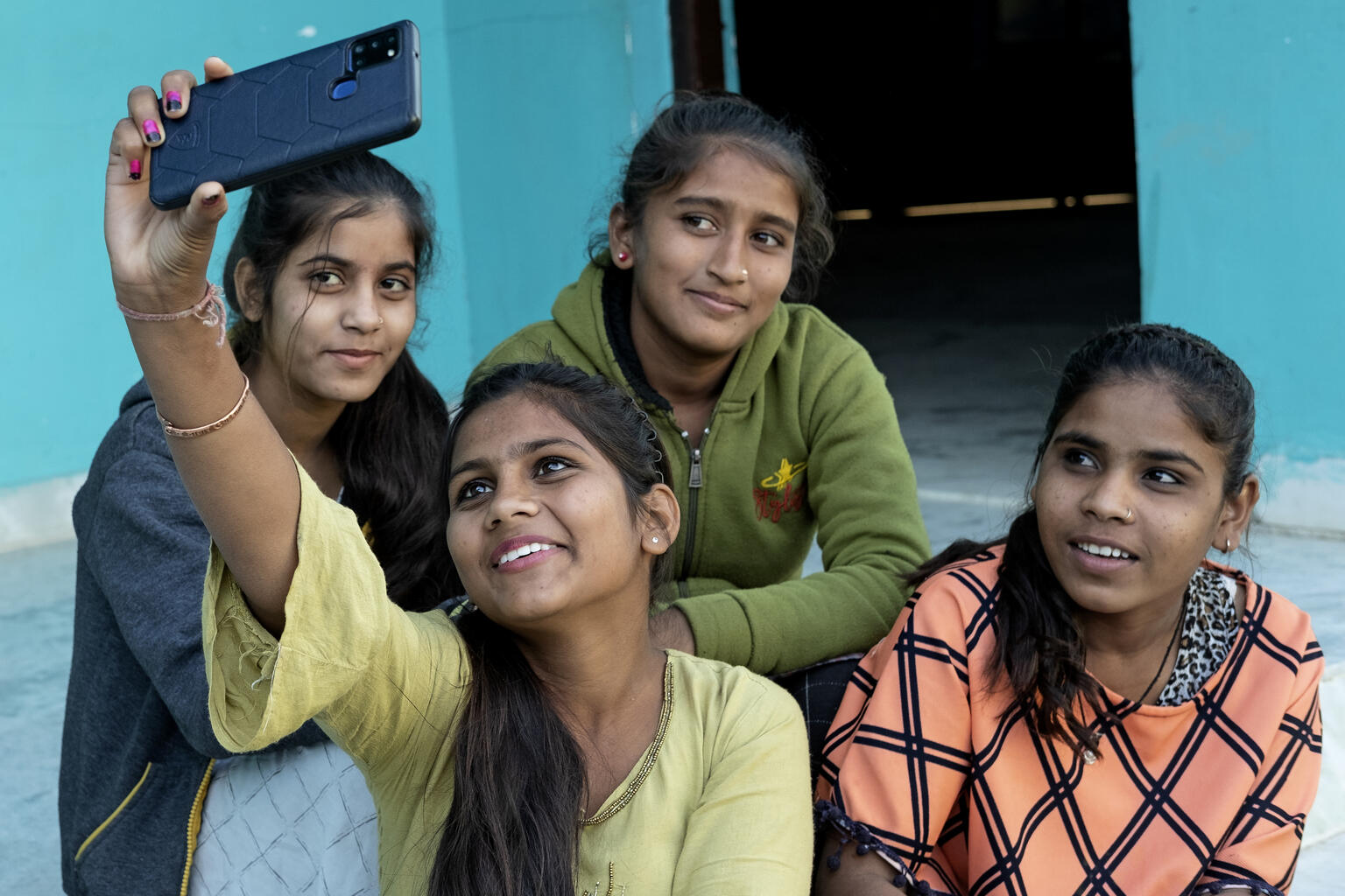 Children in India take photos on a phone.