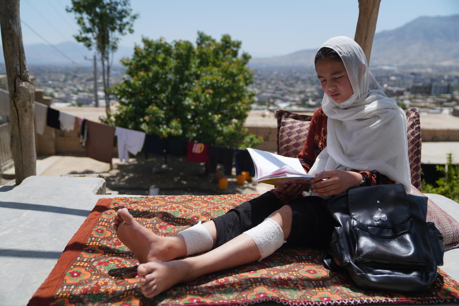 A young girl reads after her school was attacked in Afghanistan, injurying both her legs.
