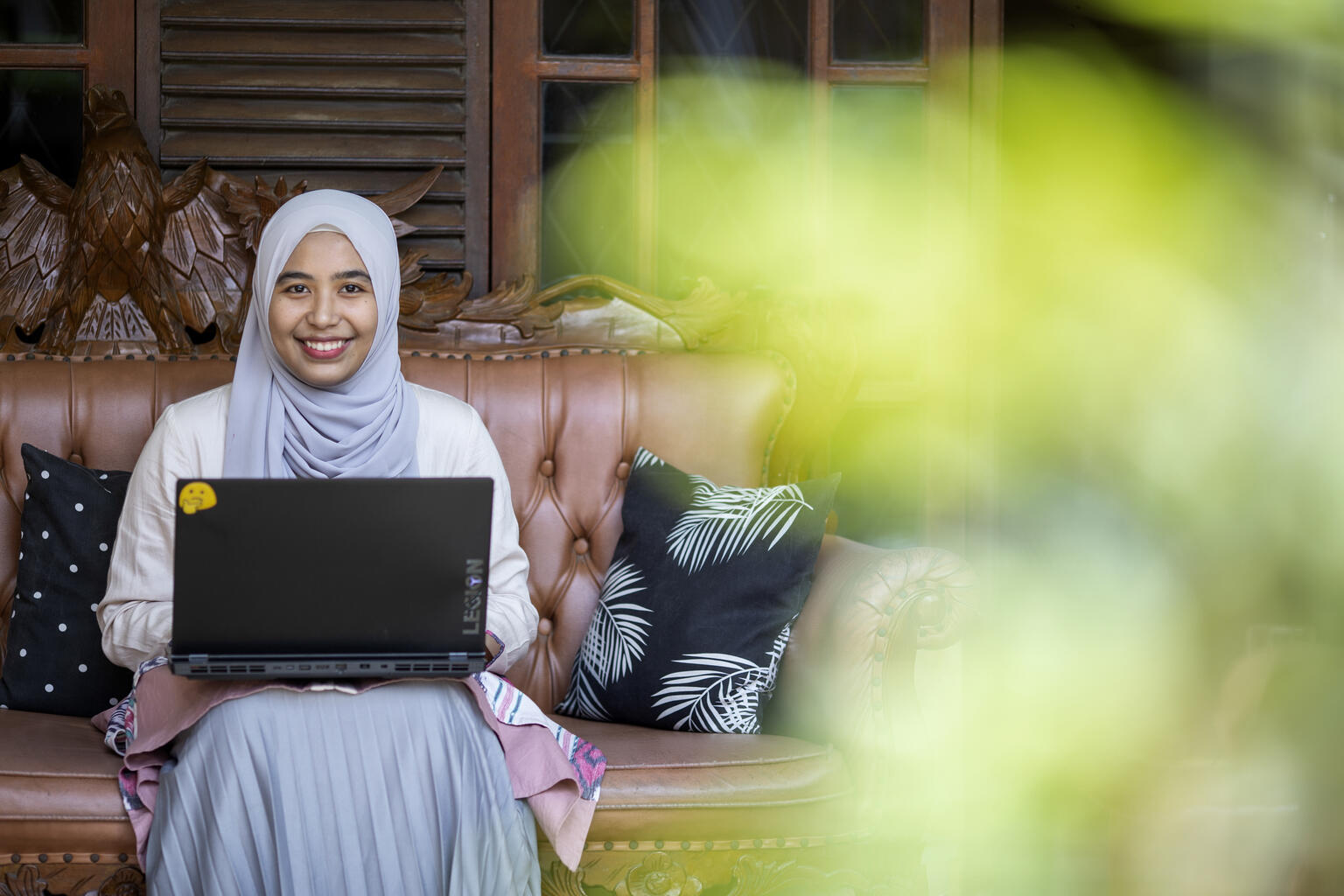 A 22-year-old poses for a photograph on her laptop in Indonesia.