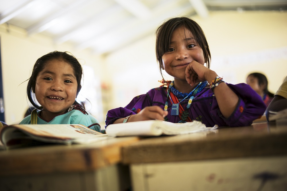 Children smile at their desks in Mexico.