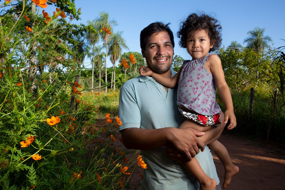 A father picks up his daughter outside their home in Paraguay. 