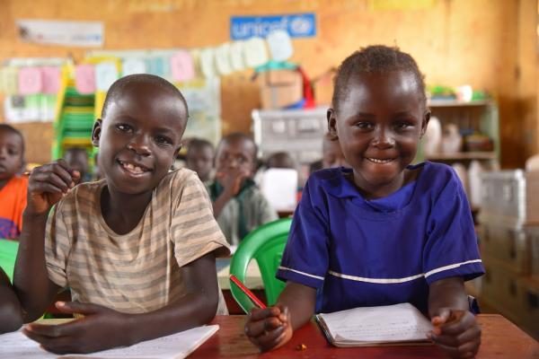 Two children in Uganda sit at a desk. 
